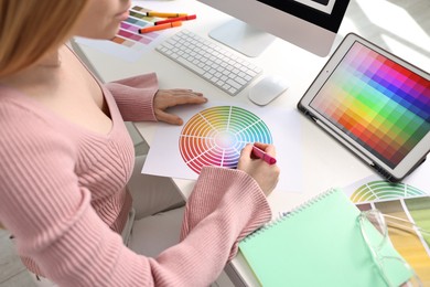 Photo of Designer working with color palette at table in office, closeup