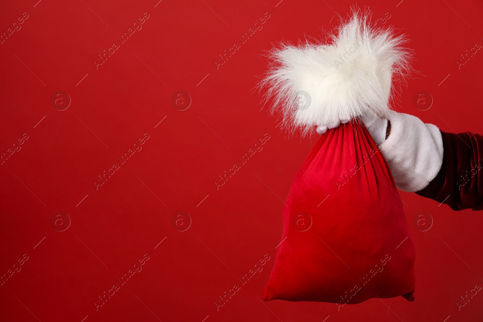 Photo of Santa Claus with bag of Christmas gifts on red background, closeup. Space for text