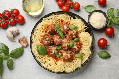 Photo of Delicious pasta with meatballs and ingredients on grey textured table, flat lay