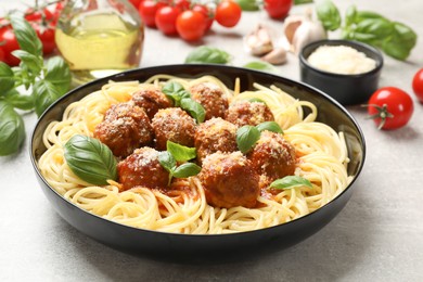 Photo of Delicious pasta with meatballs and ingredients on grey textured table, closeup