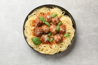 Delicious pasta with meatballs on grey textured table, top view