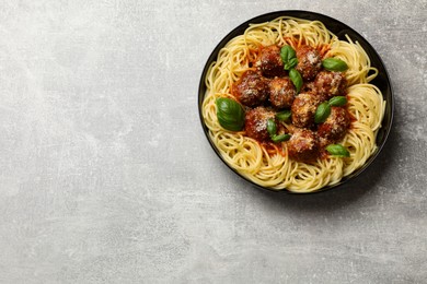 Delicious pasta with meatballs on grey textured table, top view. Space for text