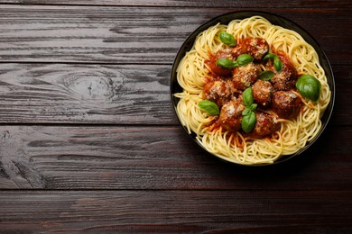 Photo of Delicious pasta with meatballs on wooden table, top view. Space for text