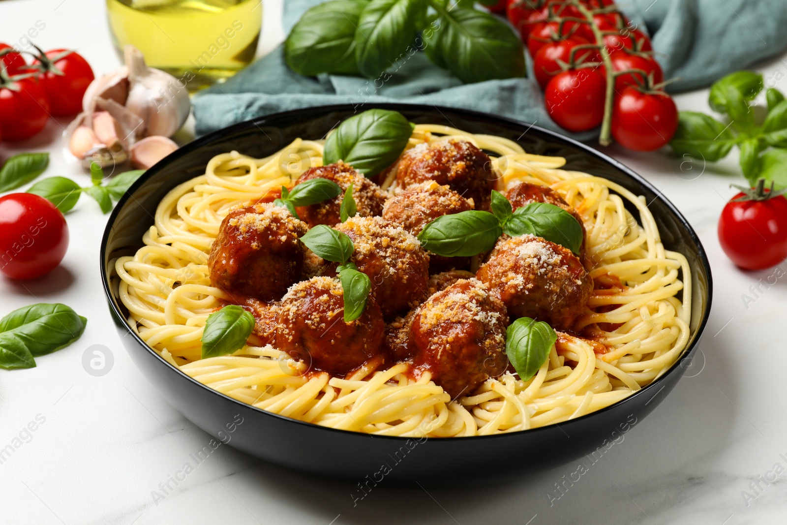 Photo of Delicious pasta with meatballs and ingredients on white marble table, closeup