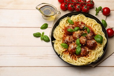 Photo of Delicious pasta with meatballs and ingredients on wooden table, flat lay. Space for text