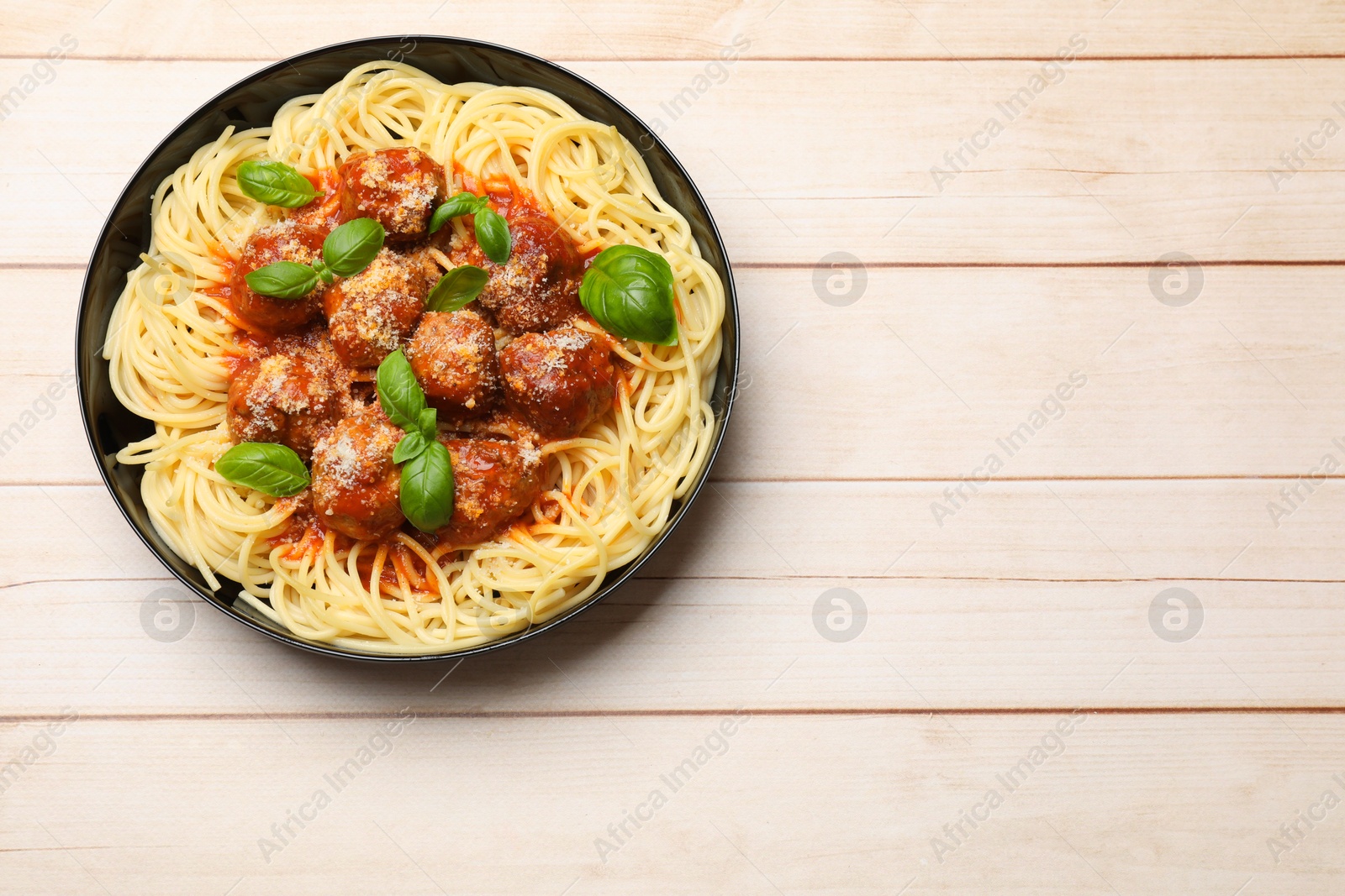 Photo of Delicious pasta with meatballs on wooden table, top view. Space for text