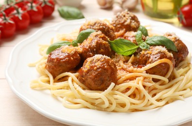 Delicious pasta with meatballs and ingredients on light wooden table, closeup