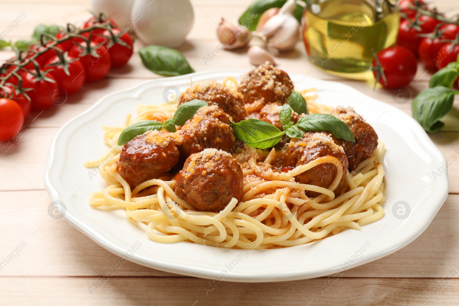 Photo of Delicious pasta with meatballs and ingredients on light wooden table, closeup