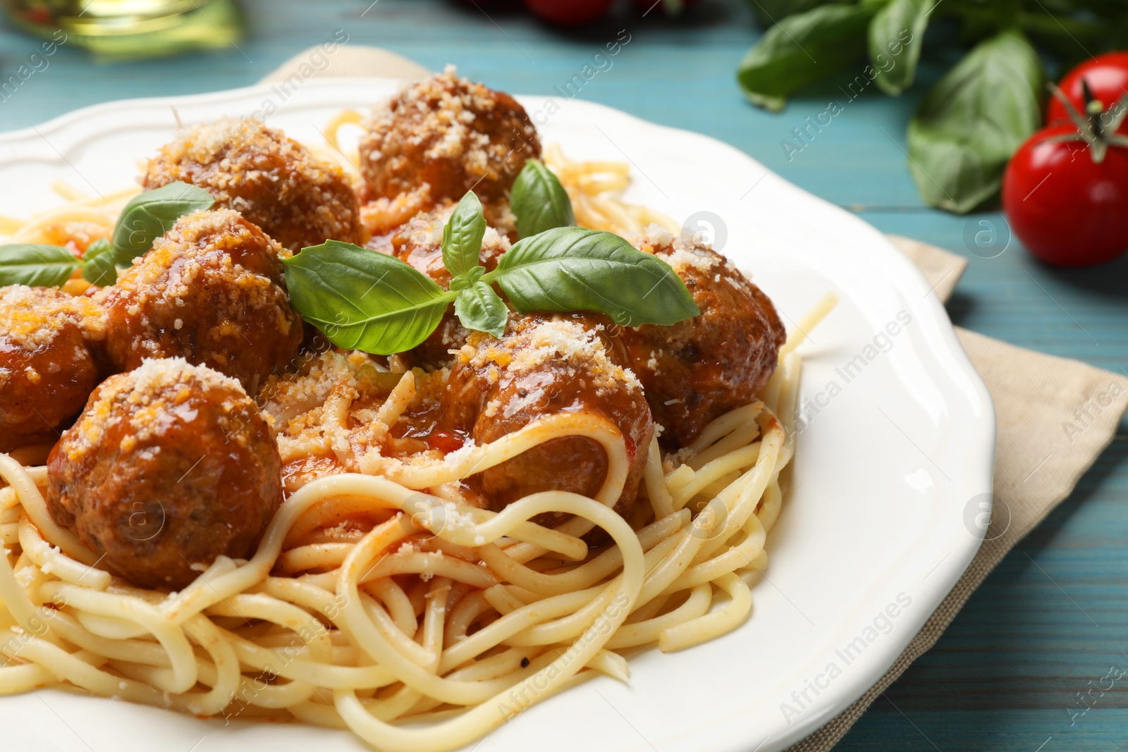 Photo of Delicious pasta with meatballs and ingredients on light blue wooden table, closeup