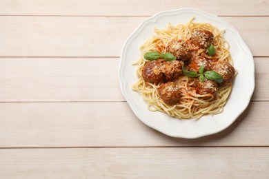 Photo of Delicious pasta with meatballs on light wooden table, top view. Space for text