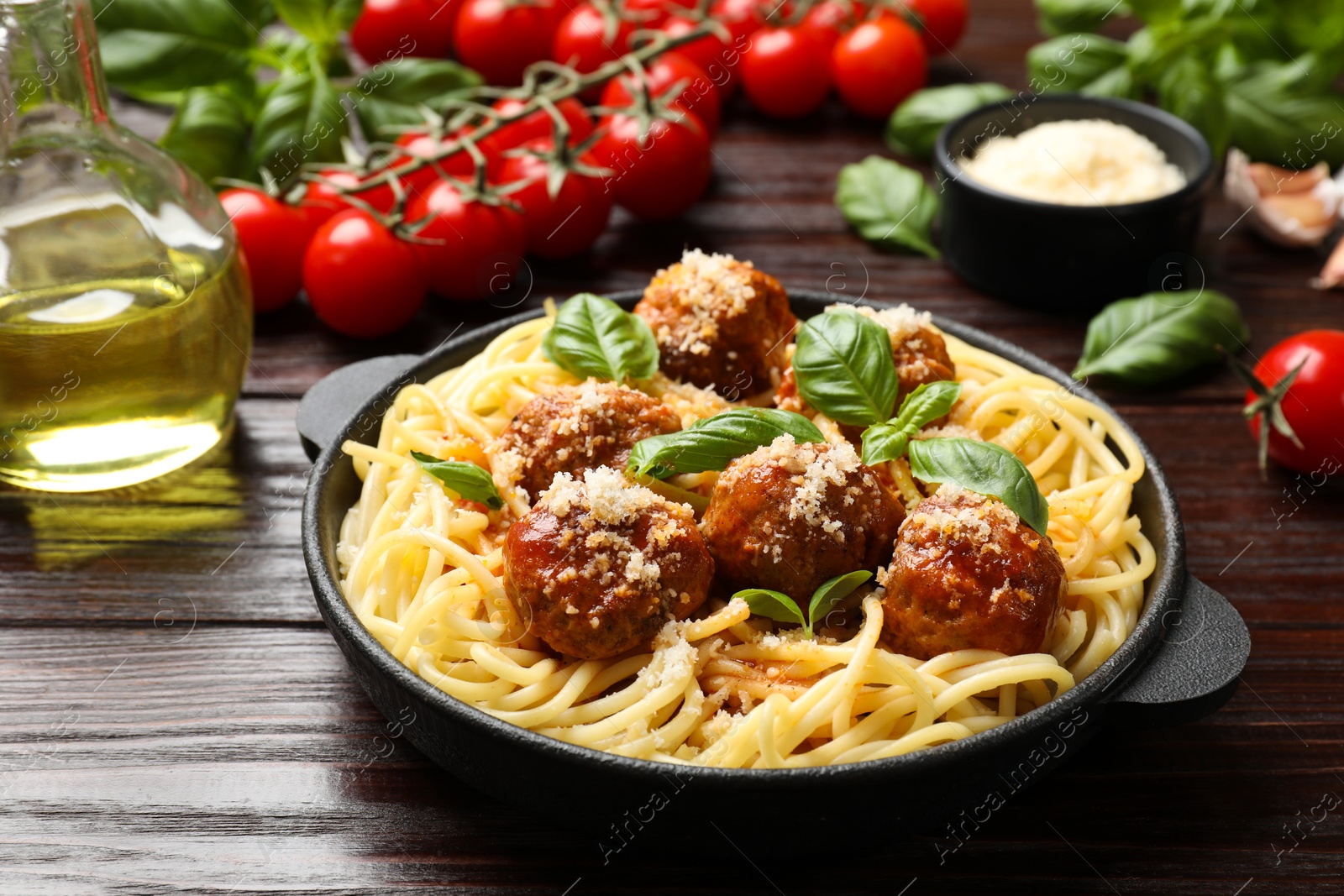 Photo of Delicious pasta with meatballs and ingredients on wooden table, closeup