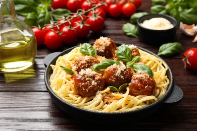 Photo of Delicious pasta with meatballs and ingredients on wooden table, closeup