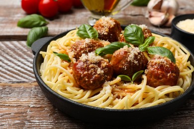 Photo of Delicious pasta with meatballs and ingredients on wooden table, closeup