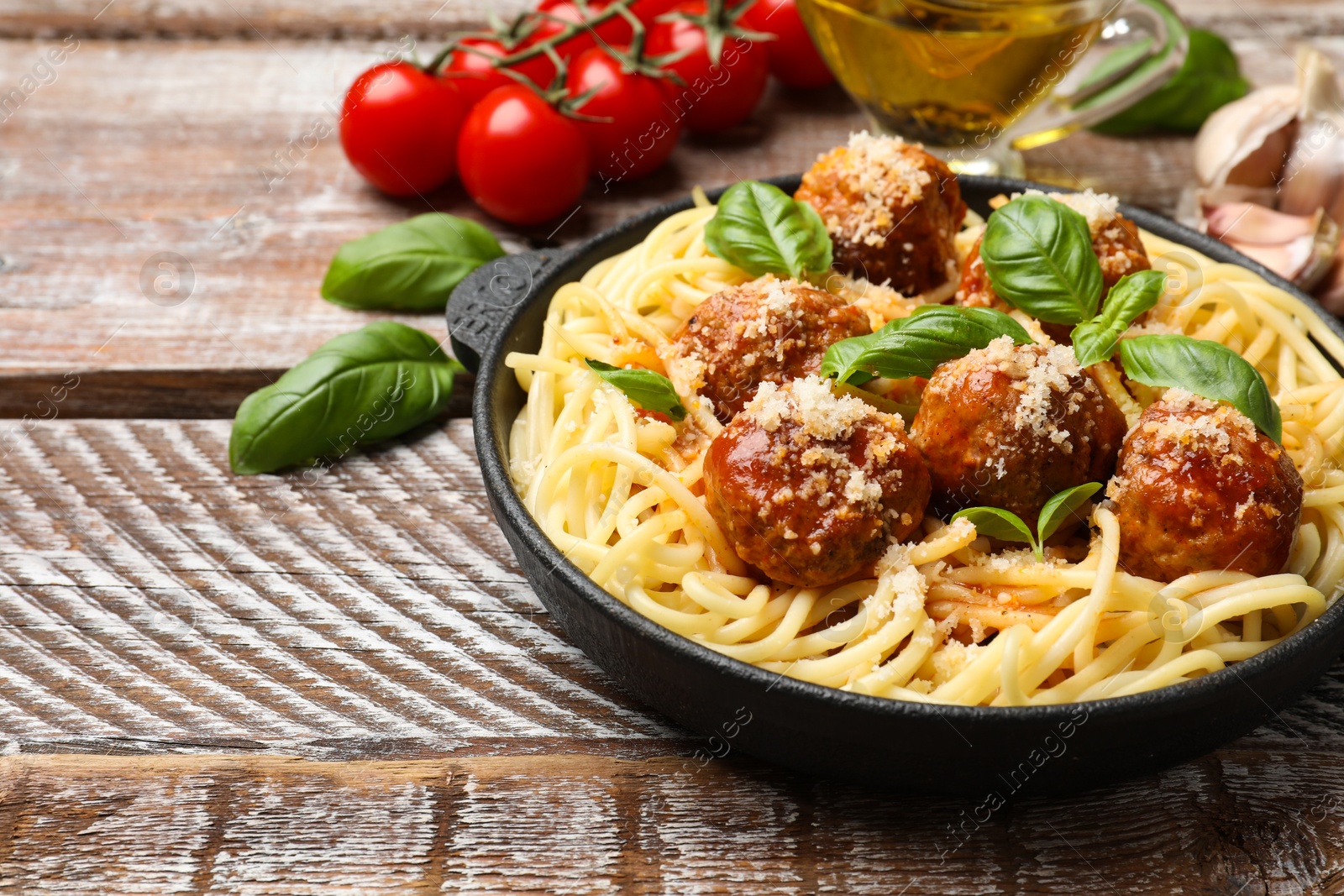 Photo of Delicious pasta with meatballs and ingredients on wooden table, closeup