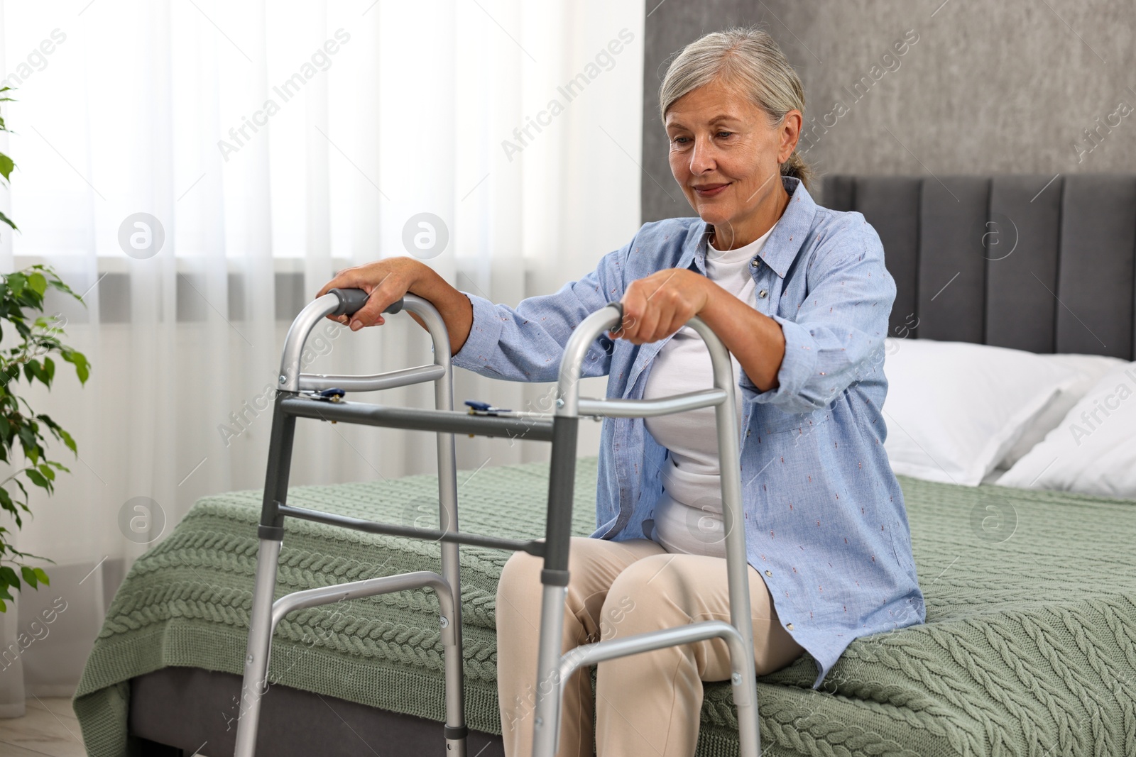 Photo of Senior woman with walking frame on bed at home