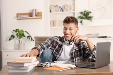 Photo of Student with headphones studying at table indoors