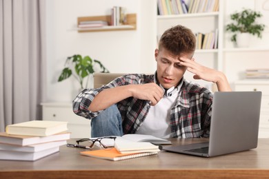 Photo of Student with headphones studying at table indoors