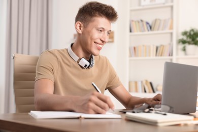 Photo of Student studying with laptop at table indoors