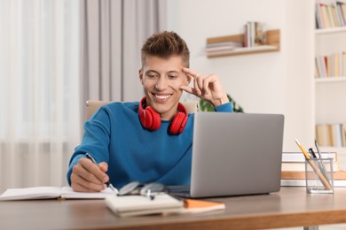 Photo of Student with headphones studying at table indoors