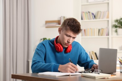 Photo of Student with headphones studying at table indoors