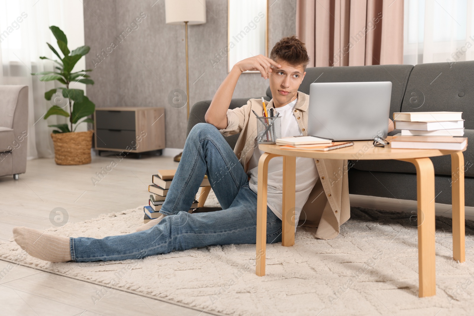 Photo of Student studying with laptop on floor at home