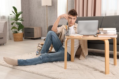 Student studying with laptop on floor at home