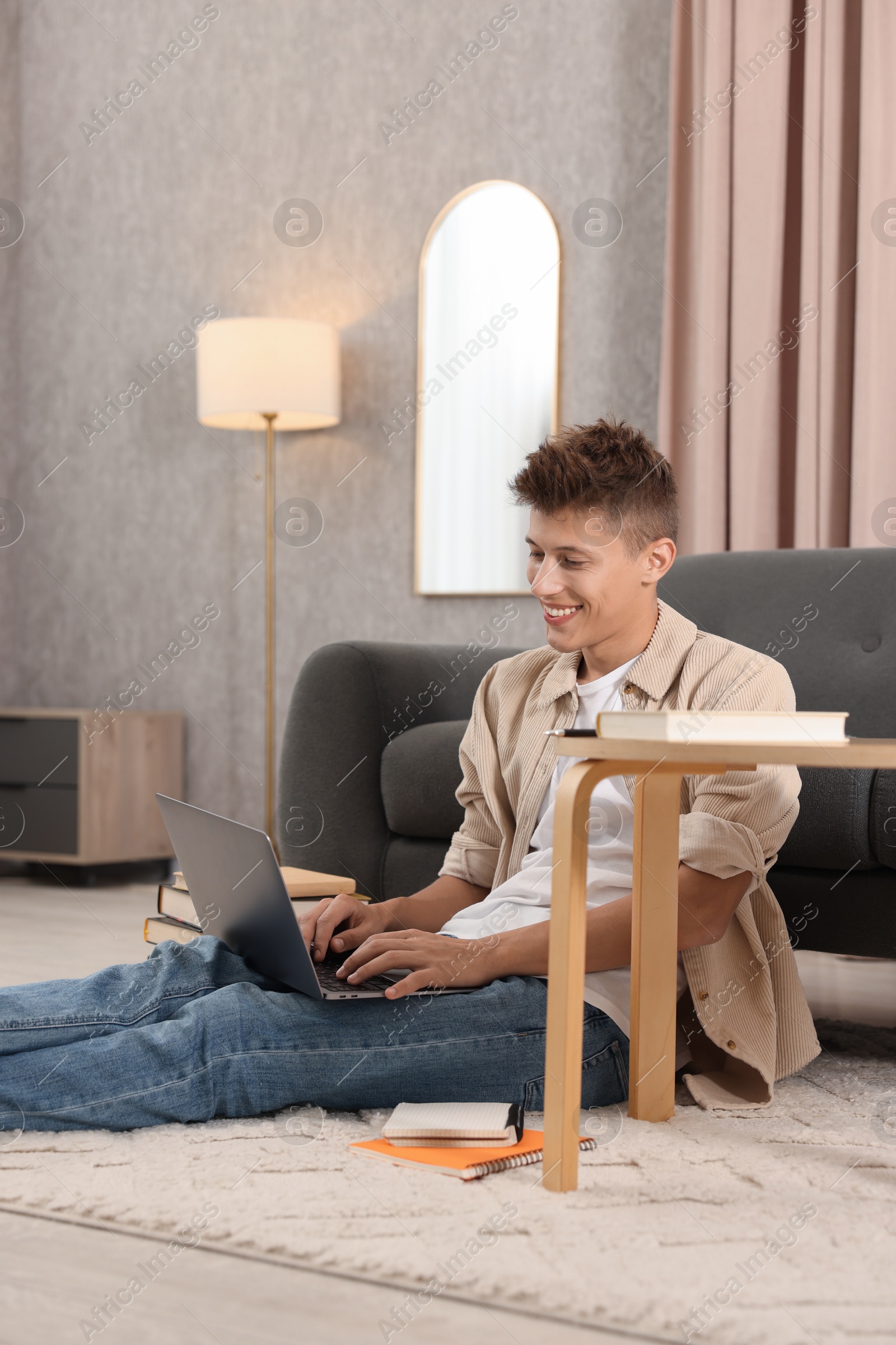 Photo of Student studying with laptop on floor at home