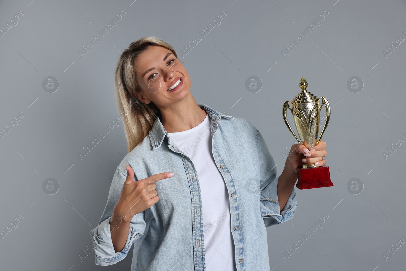 Photo of Happy winner with golden trophy cup on gray background