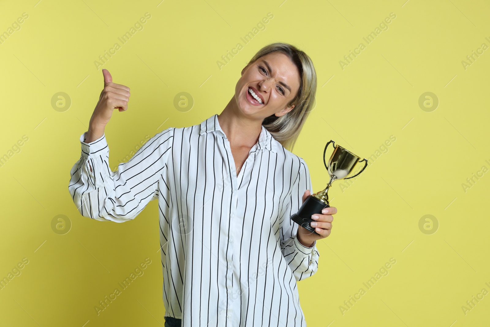 Photo of Happy winner with golden trophy cup on yellow background