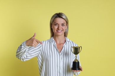 Photo of Happy winner with golden trophy cup on yellow background