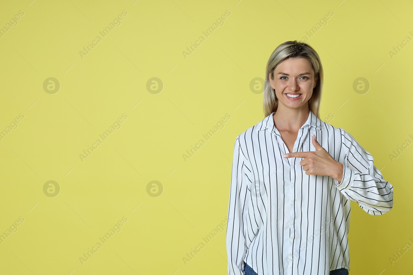 Photo of Happy winner pointing at something on yellow background, space for text