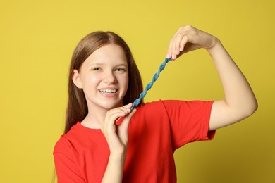 Photo of Happy teenage girl holding tasty gummy candy on yellow background