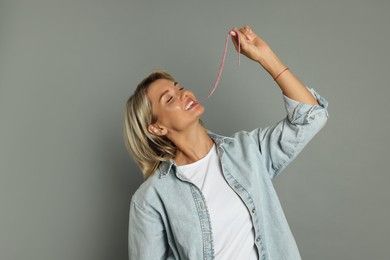 Photo of Young woman eating tasty gummy candy on grey background