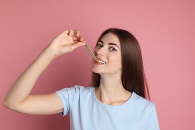 Photo of Young woman eating tasty rainbow sour belt on pink background