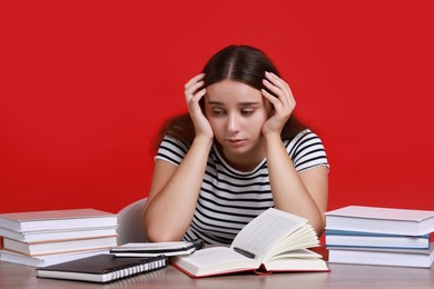 Photo of Young student having stress before exam at desk against red background