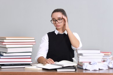 Photo of Young student having stress before exam at desk against grey background