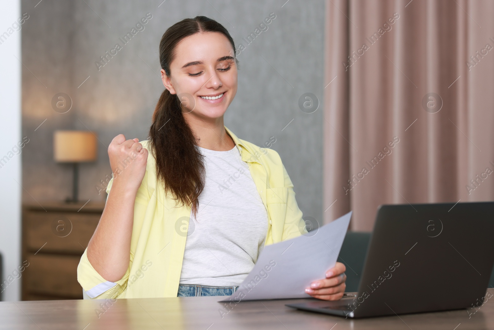 Photo of Young student with sheet happy about her good exam result at workplace