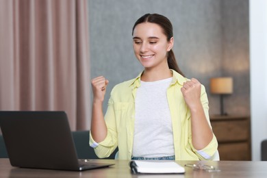 Photo of Young student with laptop happy about her good exam result at workplace