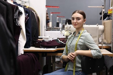 Photo of Young woman with sewing machine working in professional workshop