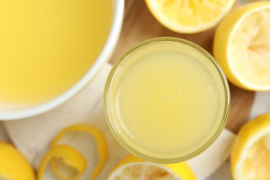 Photo of Fresh lemon juice and squeezed fruits on table, flat lay