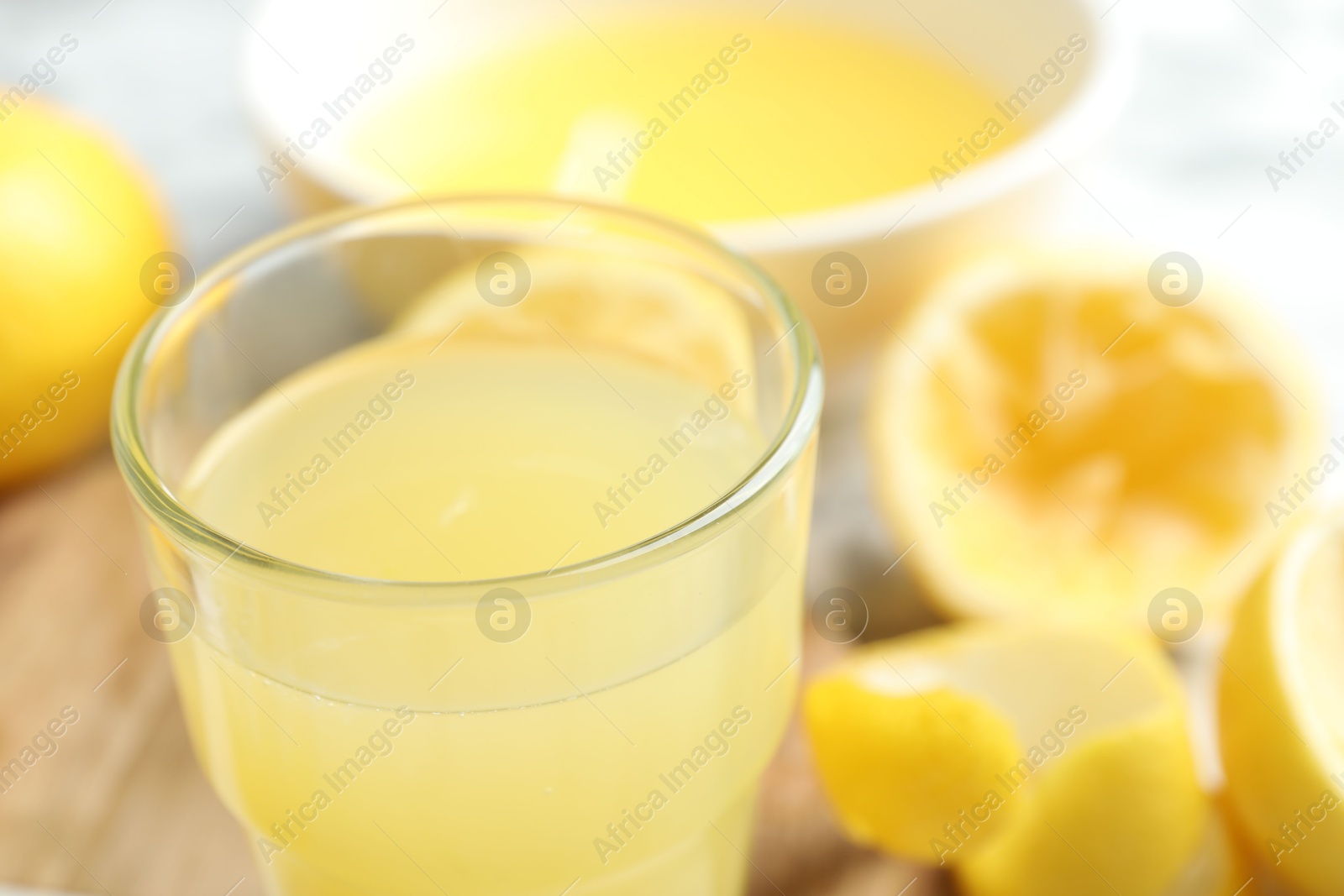 Photo of Glass of fresh lemon juice and squeezed fruits on table, closeup