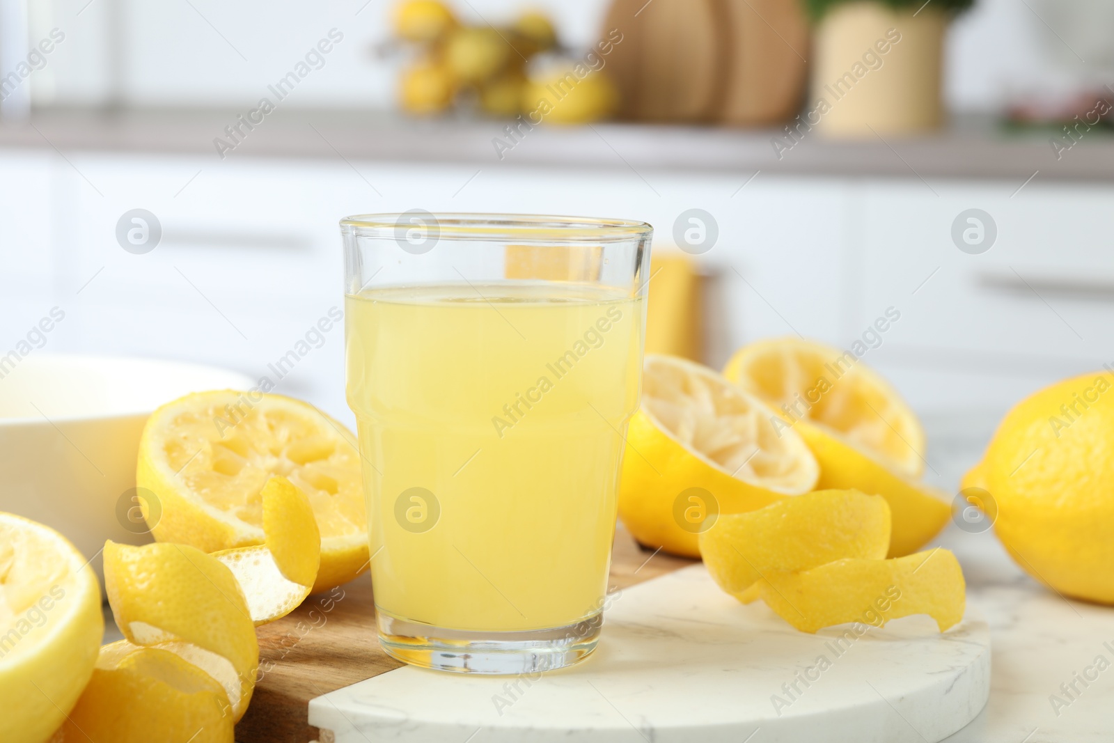 Photo of Glass of fresh lemon juice and squeezed fruits on table