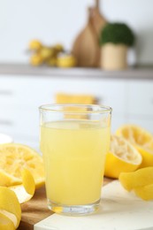 Glass of fresh lemon juice and squeezed fruits on table