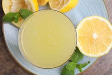 Photo of Glass of lemon juice and fresh fruits on wooden table, top view