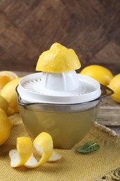 Photo of Juicer and fresh lemons on wooden table