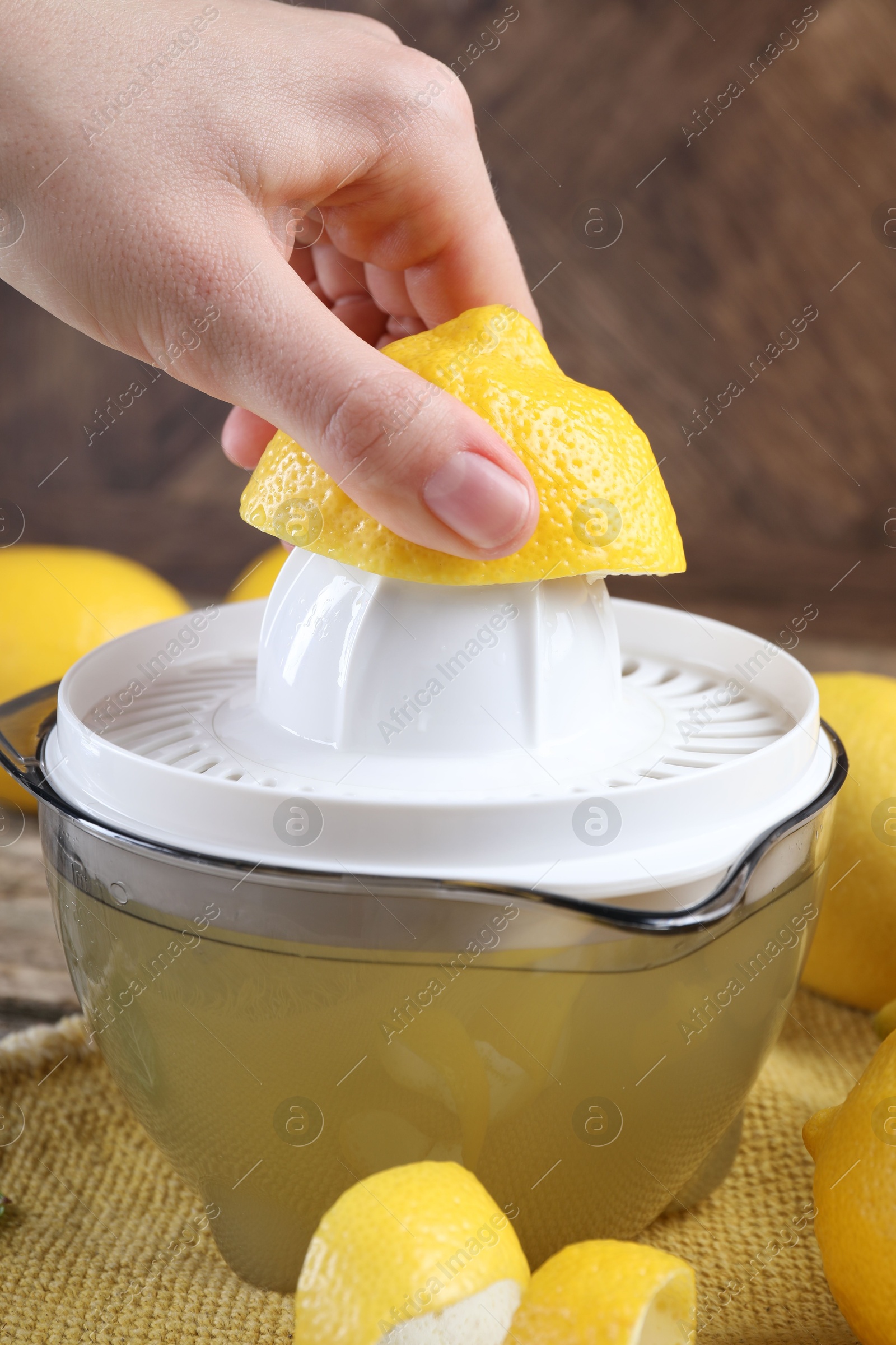 Photo of Woman with lemon using juicer at wooden table, closeup