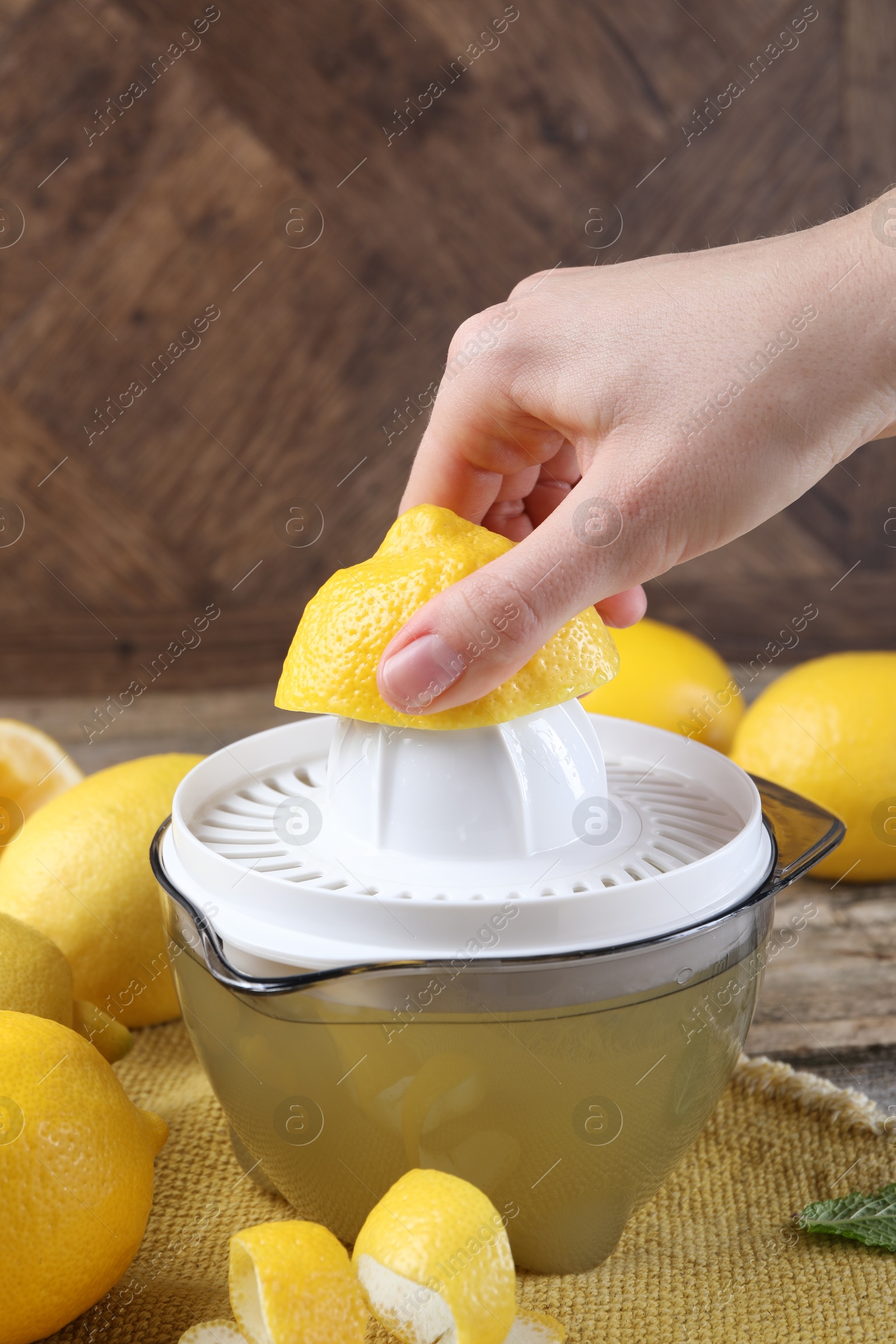 Photo of Woman with lemon using juicer at wooden table, closeup