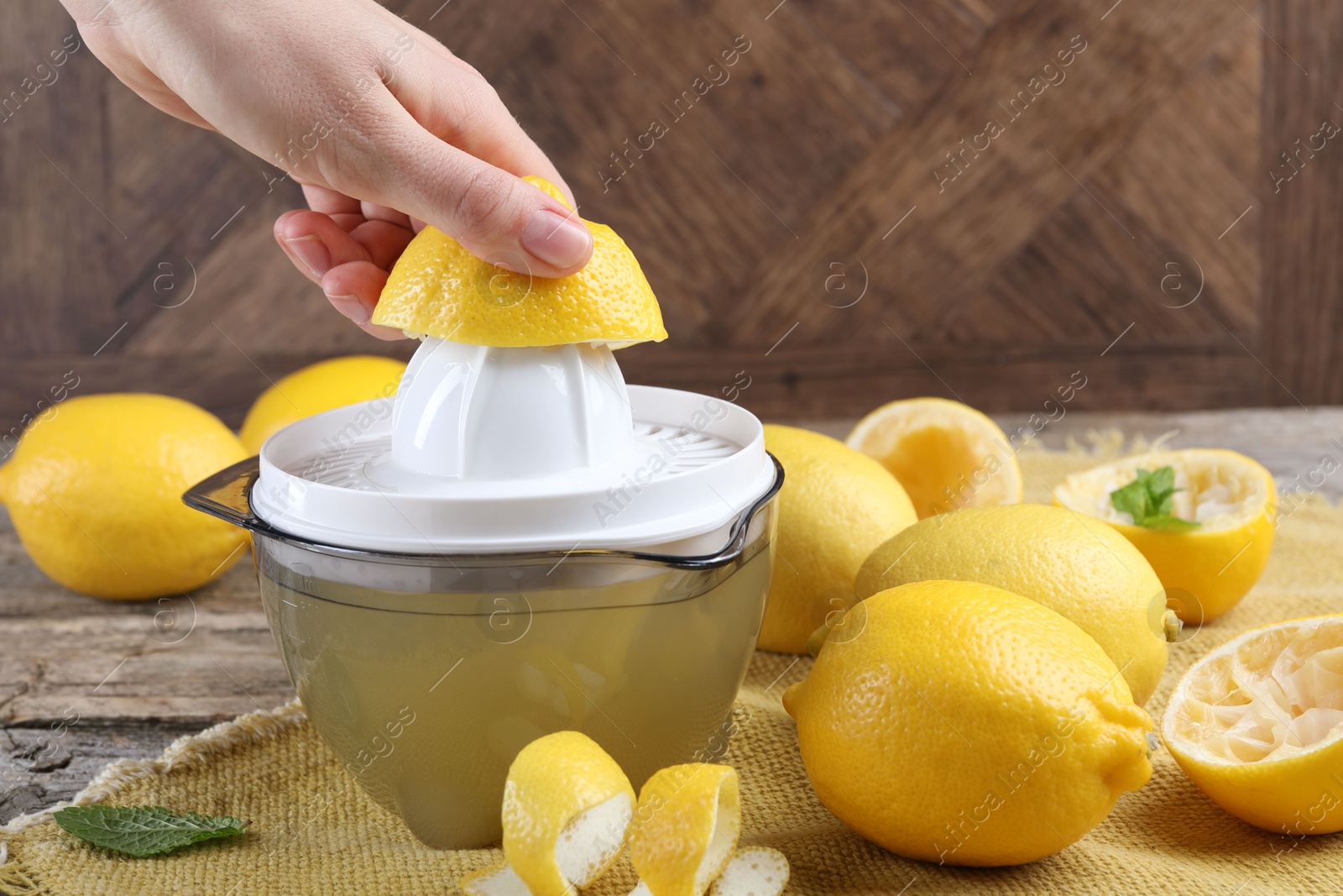 Photo of Woman with lemon using juicer at wooden table, closeup