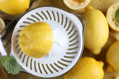 Photo of Juicer and fresh lemons on wooden table, top view