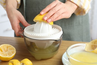 Photo of Woman with lemon using juicer at wooden table, closeup